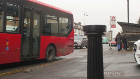 Red-English-bus-departing-at-a-bus-stop