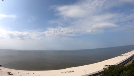 time-lapse-daytime-view-of-beach---ocean,-many-active-clouds,-wind-blowing-water-all-around---14th-story-view-of-nearly-wave-less-beach-in-gulf