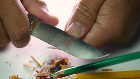 Footage-of-hands-slowly-sharpening-a-pencil-and-some-coloured-pencils-with-a-sharp-knife
