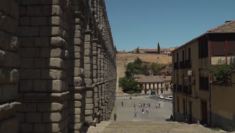 POV-view-walking-down-steps-next-to-ancient-aqueduct-watercourse-in-Segovia,-Spain-near-Madrid-SLOW-MOTION