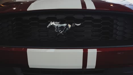 Verchromtes-Ford-Mustang-Kühlergrill-Logo-Emblem-Auf-Rotem-Auto-Mit-Rennstreifen