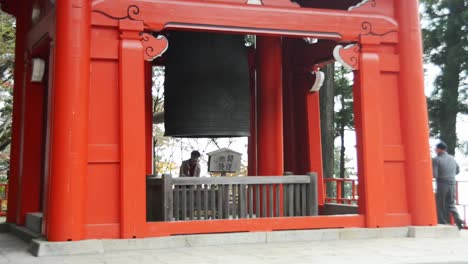 Mujer-Japonesa-Usando-Una-Campana-En-Un-Santuario-Rojo-En-El-Monte-Hiei-zan,-Kyoto,-Japón