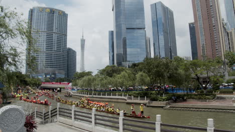 Chinese-people-paddle-and-hit-drums-on-a-dragon-boat-during-dragon-boat-festival-in-downtown-of-Guangzhou-with-the-view-of-CBD-buildings-and-Canton-Tower-in-background,-Guangdong,-China