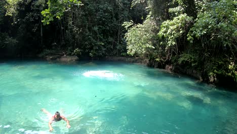 girl-in-life-jacket-and-helmet-jumps-to-blue-water-in-Kawasan-Falls