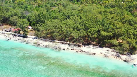 Sandy-path-going-through-lush-vegetation-of-tropical-island-alongside-white-beach-washed-by-turquoise-lagoon-with-rocky-seabed-in-coastline-of-Indonesia