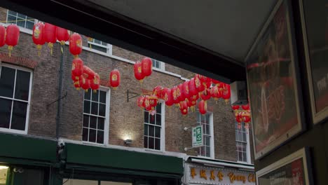 London's-Chinatown-Chinese-lantern-reveal-from-alleyway-swaying-in-the-wind-on-an-overcast-day