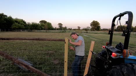 Man-With-A-Hammer-Securing-A-Nail,-Repairing-A-Farm-Fence-In-Flat-Rock,-Michigan,-USA---Medium-Shot