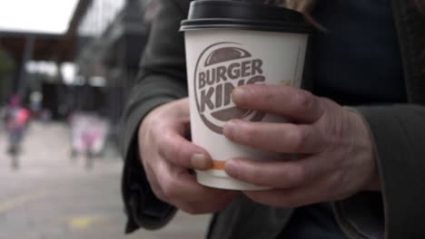 Hands-holding-Burger-King-coffee-take-out-cup-of-coffee-in-city