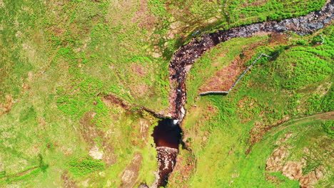 High-aerial-top-down-shot-of-a-winding-stream-in-the-middle-of-the-countryside,-bright-summers-day