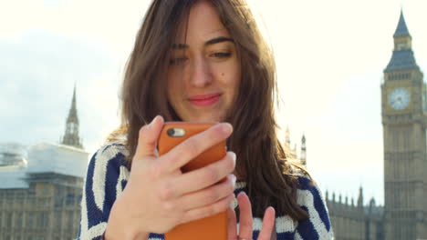 A-young-woman-smiling-and-using-her-smartphone