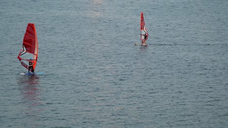 Woman-windsurfing-on-Han-river-at-Sunset-Seoul,-Rider-Person-maneuvering-the-entire-rig-of-Sail-and-changing-the-grip-on-the-boom-to-change-the-moving-direction