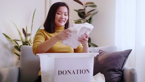Woman-selecting-clothes-for-donation-and-putting-in-box