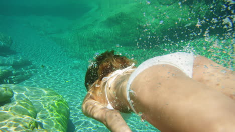 Woman-in-white-bikini-swimming-underwater-in-clear