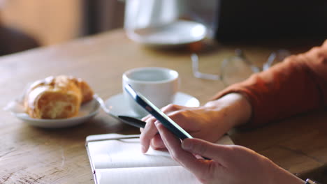 Coffee-shop,-smartphone-and-hands-with-notebook