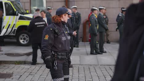 Policewoman-inspevting-Karl-Johan,-Oslo-during-military-parade-with-soldiers-behind