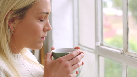 Sad-woman-drinking-tea-while-looking-out