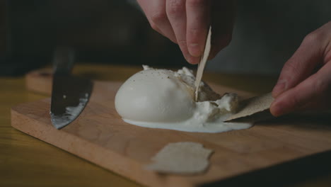 Scooping-soft-and-creamy-artisanal-Burrata-cheese-onto-a-biscuit