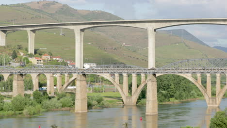 Vehicles-Driving-At-Regua-Pedestrian-Bridge-With-Ponte-Rodoviaria-da-Regua-Over-Douro-River-In-Portugal