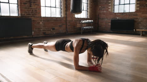 Focused-young-woman-on-the-floor-doing-planks