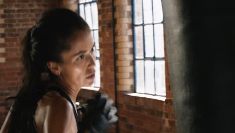 Serious-sporty-woman-hitting-a-punching-bag-during