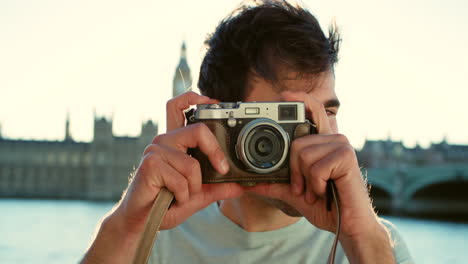 Cheerful-young-man-taking-a-photo-with-his-camera
