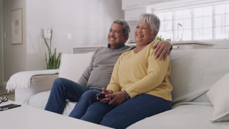 Senior-couple-laughing-while-watching-tv
