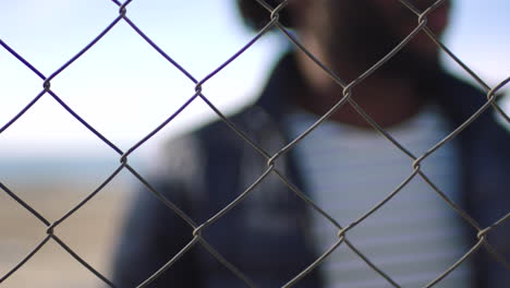 Closeup-of-man-resting-hand-on-a-chain-link-fence