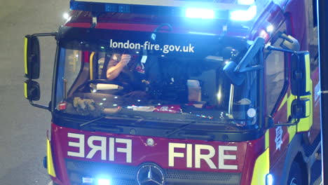 Close-up-of-a-fire-engine-with-flashing-lights-at-night-in-London,-England