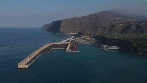 Drone-flying-over-Tazacorte-harbor-and-volcanic-black-beach,-La-Palma-island
