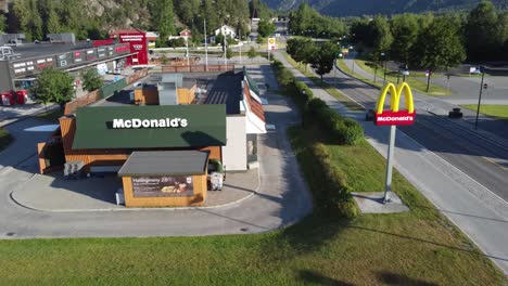 McDonalds-restaurant-and-sign-along-Norway-road---Backward-moving-aerial-at-afternoon-sunset