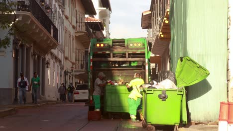 Mitarbeiter-Der-Sanitärbehörde-Arbeiten-Hart-Daran,-Die-Mülltonnen-Der-Gemeinde-Auf-Die-Ladefläche-Ihres-Müllwagens-Zu-Leeren,-Casco-Viejo,-Panama-City