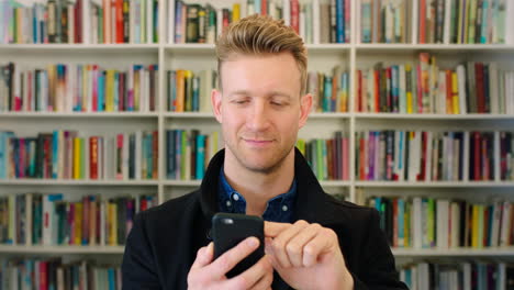Modern-man-using-his-phone-in-a-bookstore