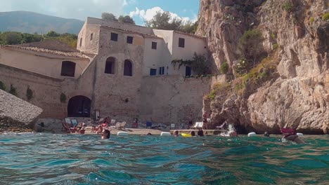 People-swim-at-Sicilian-stacks-or-Faraglioni-of-Scopello-in-Sicily,-Italy