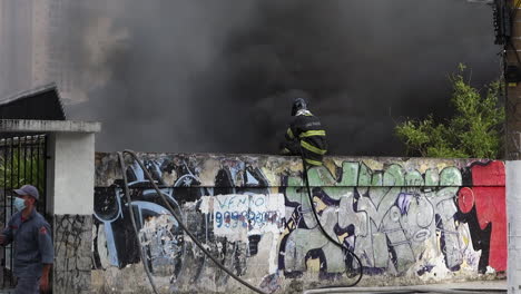 Smoky-urban-fire-scene,-firemen-fight-blaze-from-neighborhood-street,-on-Tereza-Cristina-avenue,-Ipiranga-district