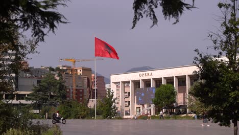 Long-view-towards-Opera-at-Skandenberg-square-in-Tirana,-Albania-with-flag-and-opera