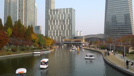 People-ride-paddle-family-boats-and-moon-boats-in-Incheon-Songdo-Central-Park---on-lake-and-stroll-on-walkways-wearing-masks-during-covid-19-in-Autumn,-South-Korea