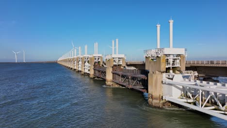 Aerial-shot-moving-past-the-locks-of-the-Eastern-Scheldt-storm-surge-barrier-in-Zeeland,-the-Netherlands,-on-a-beautiful-sunny-day