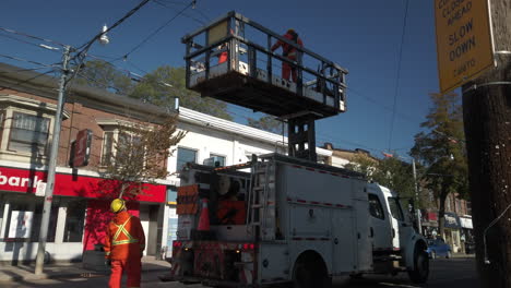 Wide-tilt-up-to-Toronto-hydro-workers-working-on-overhead-tram-lines-along-Queen-Street-East