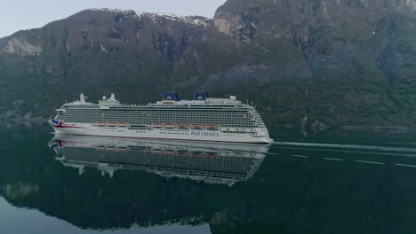 Slow-motion-shot-of-the-beautiful-landscape-with-a-large-cruise-ship-on-the-calm-ocean-water-in-a-huge-mountains-background-on-a-mild-climate-at-Norway---flam