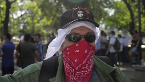 Ein-Guerillakriegsveteran-Trägt-Einen-Che-Guevara-Hut-Und-Ein-Rotes-Kopftuch,-Um-Sein-Gesicht-Während-Eines-Friedlichen-Protests-Gegen-Die-Politik-Des-Derzeitigen-Präsidenten-Nayib-Bukele-Zu-Bedecken-–-Zeitlupe