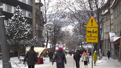 Shopping-street-in-Zakopane,-Poland-with-horse-carriage-warning-sign