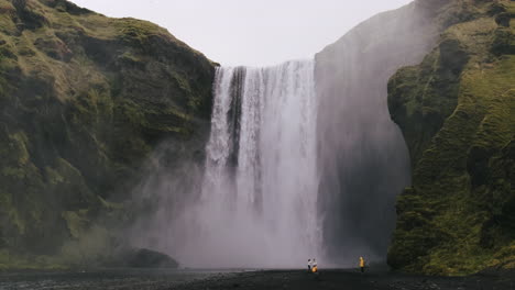 Photographers-taking-photos-at-base-of-Skogafoss-Waterfall,-Iceland