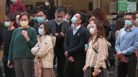 Menschenmassen-Tragen-Gesichtsmasken-Als-Vorbeugende-Maßnahme-Gegen-Die-Ausbreitung-Des-Coronavirus,-Während-Sie-An-Einer-Straßenampel-In-Hongkong-Warten
