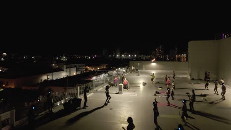 Flyover-of-Miami-rooftop-Zumba-class-to-city-traffic-below-at-night
