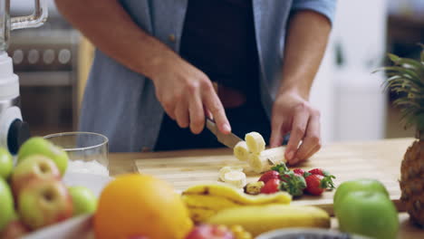 a-young-man-slicing-bananas-in-the-kitchen-at-home