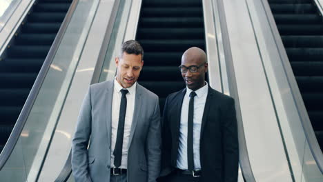 Smiling-diverse-businessmen-on-escalator-standing