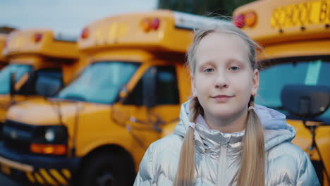 Portrait-of-a-schoolgirl-against-the-background-of-yellow-school-buses