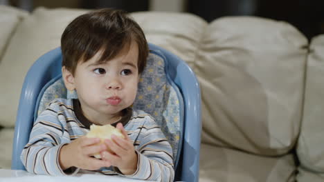 A-two-year-old-eats-a-juicy-red-apple.-Sits-in-a-high-chair