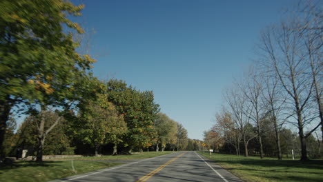 A-trip-by-car-on-a-clear-autumn-day,-a-view-from-the-car-window.-Drive-on-a-typical-American-road