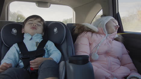 Sleeping-children-drive-in-the-back-seat-of-the-car.-Asian-baby-sleeps-in-a-child-car-seat,-a-girl-naps-next-to-her.